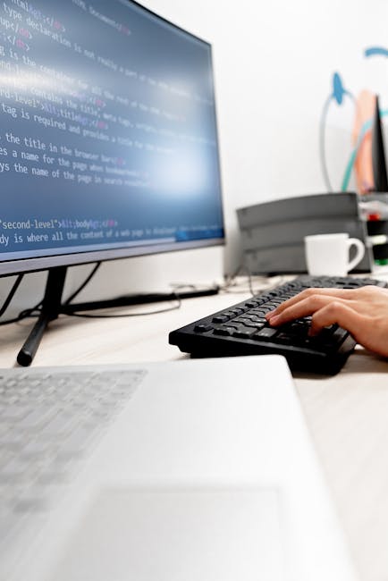 The image displays a close-up view of a computer screen showing lines of HTML code with various tags, attributes, and colour-coded text on a dark background. Visible elements include heading tags, ima